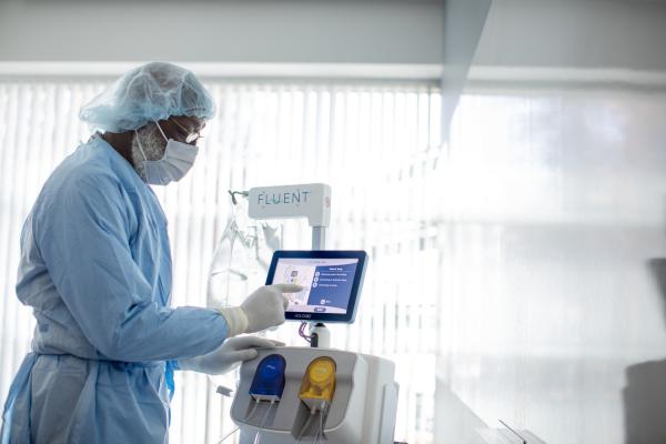 Medical professional interacting with a fluid management system during a hysteroscopic procedure in a clinical setting. 