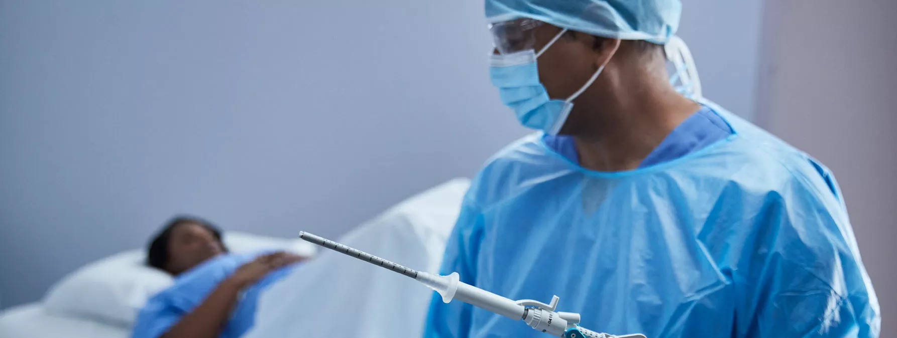 Surgeon holding NovaSure instrument with patient on hospital bed in background