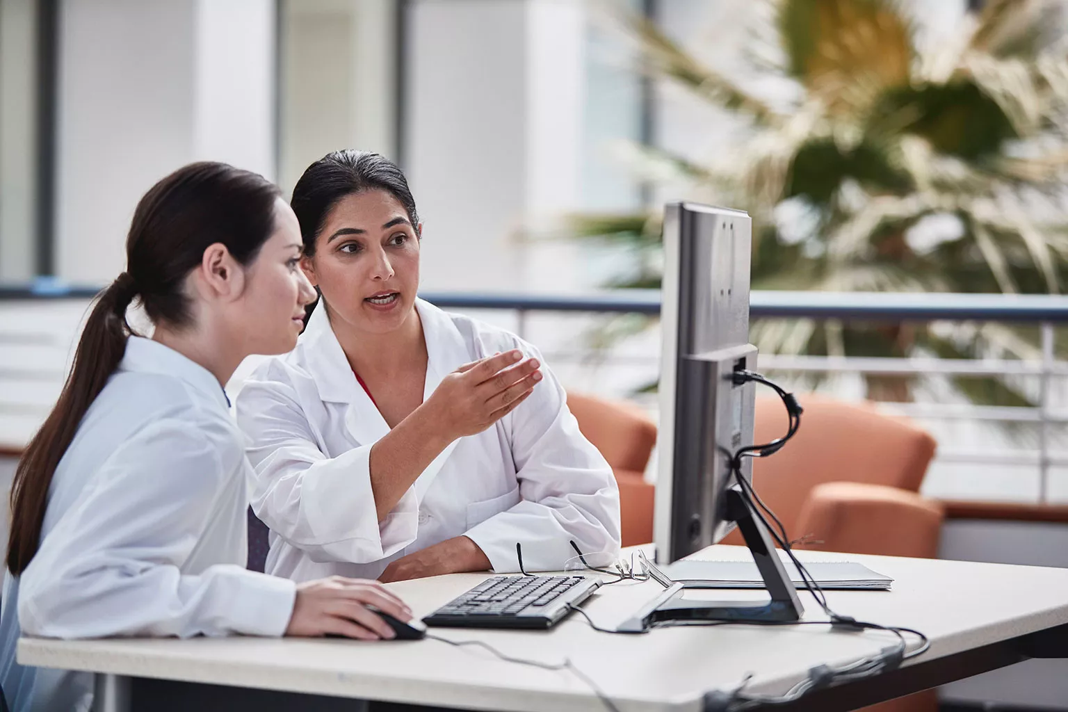 lab technicians viewing a monitor in a lab setting.