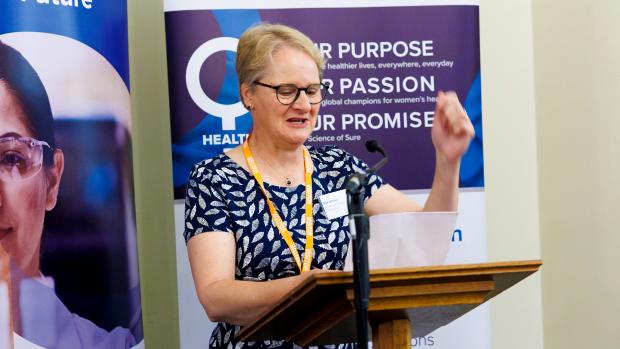 Women passionately delivering speech with two vertical banners behind her
